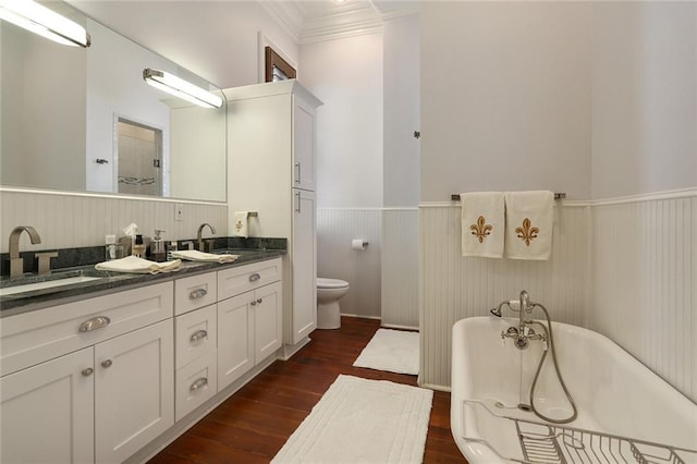 2026 Camp St, New Orleans, LA 70130 - bathroom with a wainscoted wall, double vanity, wood finished floors, toilet, and a freestanding bath