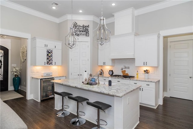 201 Jardin Loop, Covington, LA 70433 - kitchen with wine cooler, white cabinetry, tasteful backsplash, light stone counters, and a kitchen breakfast bar