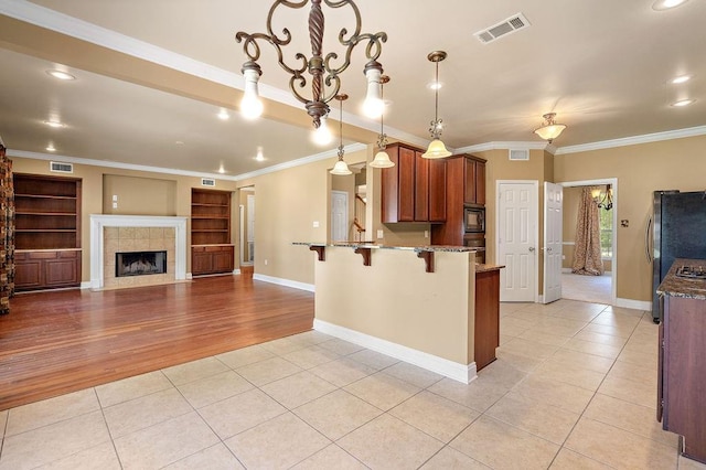 1134 Belair Blvd, Slidell, LA 70460 - kitchen with light tile patterned floors, a breakfast bar area, a peninsula, black microwave, and light stone countertops