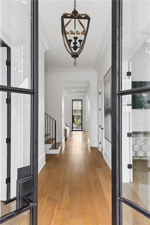 3804 Prytania St, New Orleans, LA 70115 - foyer with a chandelier, stairs, ornamental molding, wood finished floors, and baseboards