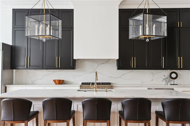 3804 Prytania St, New Orleans, LA 70115 - kitchen featuring light stone counters, decorative backsplash, dark cabinetry, a sink, and a center island with sink
