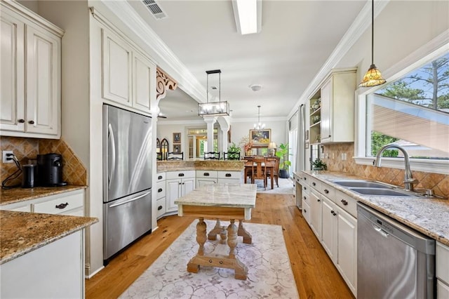 61180 Doe Run Dr, Amite, LA 70422 - kitchen featuring stainless steel appliances, a sink, a peninsula, pendant lighting, and ornamental molding