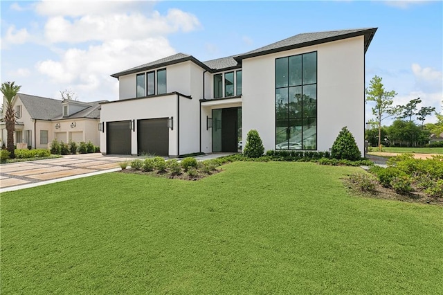 67 Hummingbird Rd, Covington, LA 70433 - contemporary house featuring an attached garage, stucco siding, driveway, and a front yard