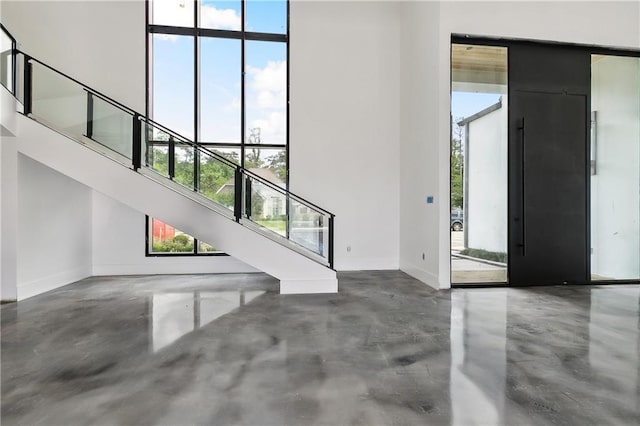 67 Hummingbird Rd, Covington, LA 70433 - foyer featuring concrete flooring, stairway, healthy amount of natural light, baseboards, and a high ceiling