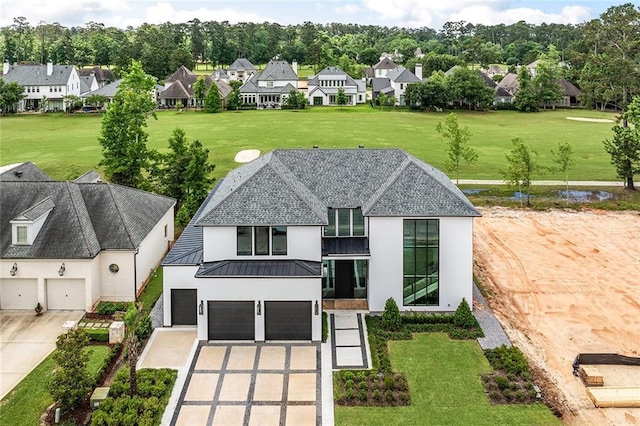 67 Hummingbird Rd, Covington, LA 70433 - view of front of property featuring driveway, stucco siding, a standing seam roof, an attached garage, and a residential view