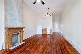 1700 S Rampart St, New Orleans, LA 70113 - unfurnished living room featuring a ceiling fan, baseboards, wood finished floors, and a fireplace
