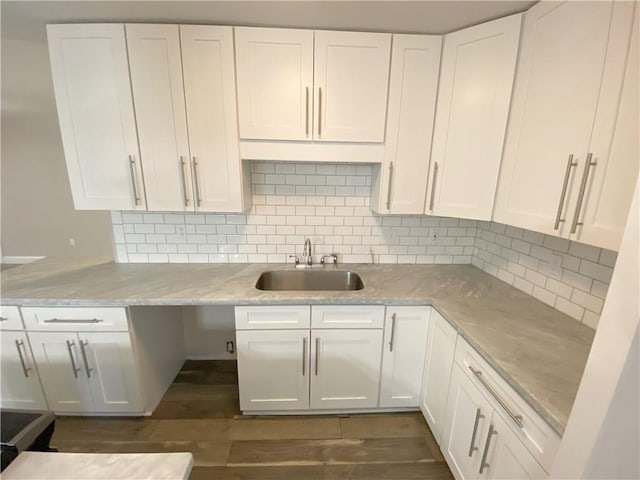 kitchen featuring a sink, white cabinetry, backsplash, dark wood-type flooring, and light stone countertops