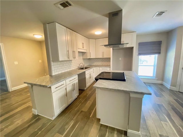 kitchen featuring a sink, cooktop, a center island, and baseboards