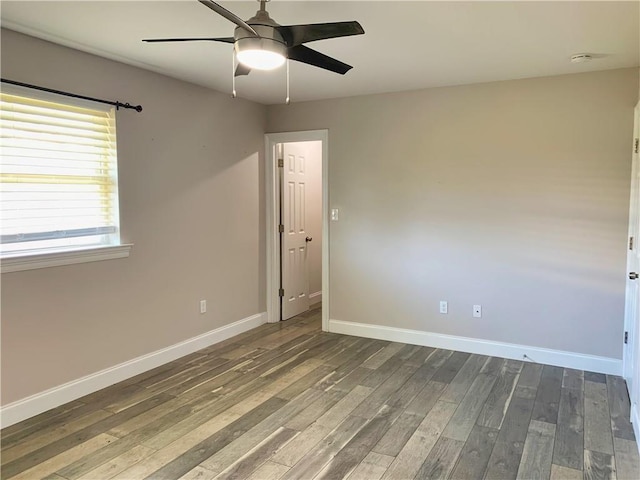 unfurnished room featuring ceiling fan, dark wood-style flooring, baseboards, and a smoke detector