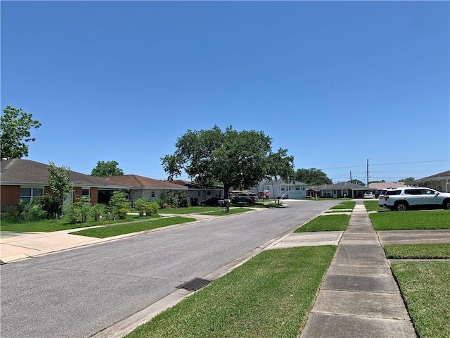 view of asphalt road with sidewalks, a residential view, and curbs