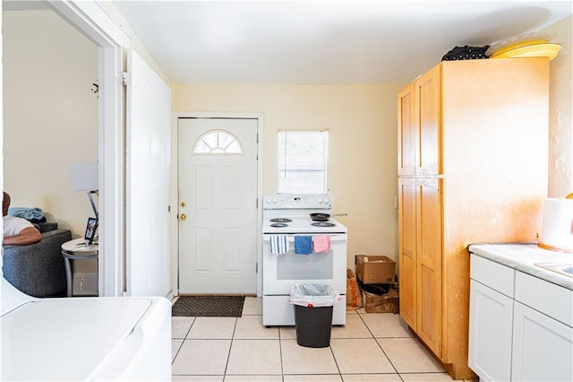 2315 Peniston St, New Orleans, LA 70115 - kitchen featuring white electric range oven, light countertops, light tile patterned floors, and white cabinetry
