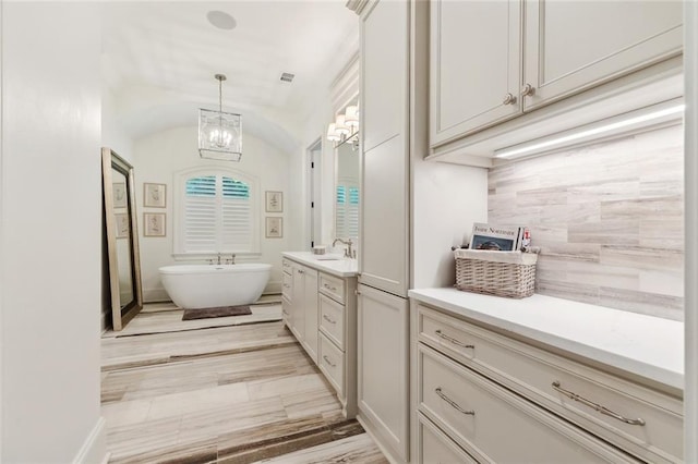 474 Trailhead Dr, Abita Springs, LA 70420 - full bathroom with vanity, a chandelier, a freestanding bath, and vaulted ceiling