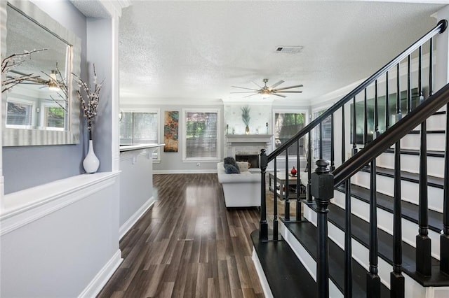 1332 Denmark Ct, Slidell, LA 70461 - stairway featuring a ceiling fan, a textured ceiling, a fireplace, baseboards, and wood finished floors