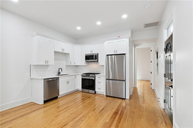 172224 St Ann St, New Orleans, LA 70116 - kitchen featuring appliances with stainless steel finishes, a sink, white cabinetry, light countertops, and light wood-style flooring