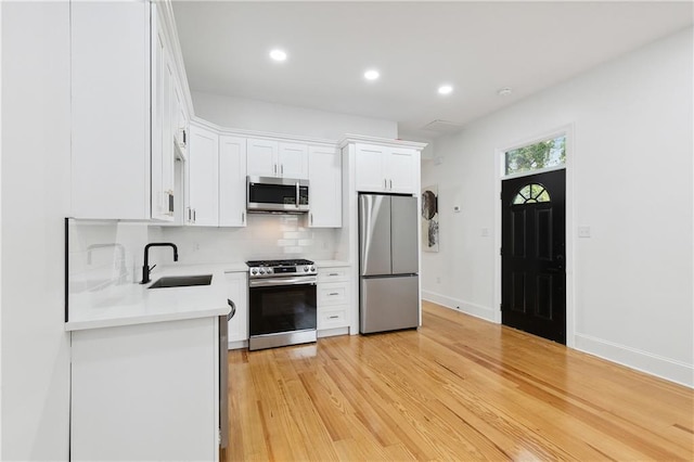 172224 St Ann St, New Orleans, LA 70116 - kitchen featuring appliances with stainless steel finishes, a sink, decorative backsplash, white cabinets, and light countertops