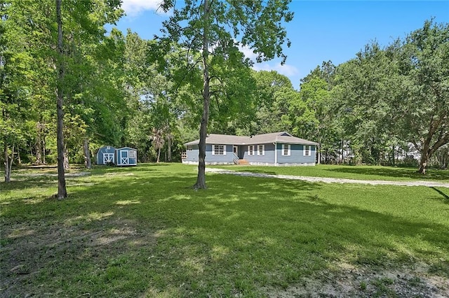 113 Roger Storme Rd, Madisonville, LA 70447 - view of front facade with a storage shed, an outdoor structure, a front yard, and a wooded view