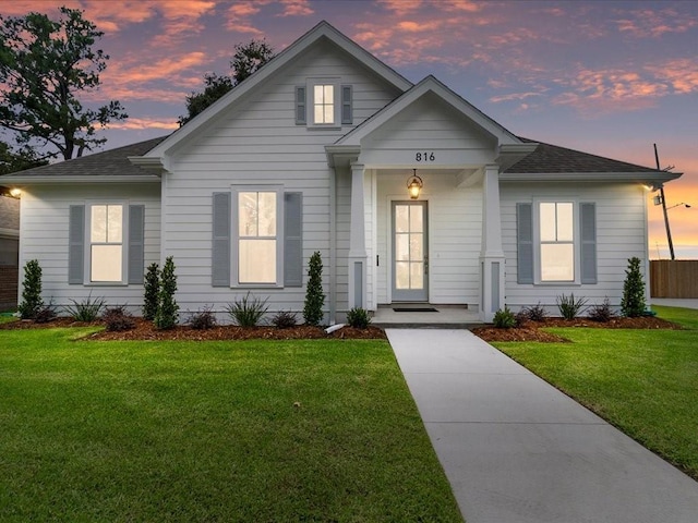 view of front of home with a yard and a shingled roof