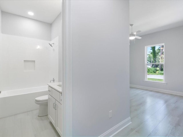 full bathroom featuring toilet, ceiling fan, vanity, shower / washtub combination, and wood finished floors