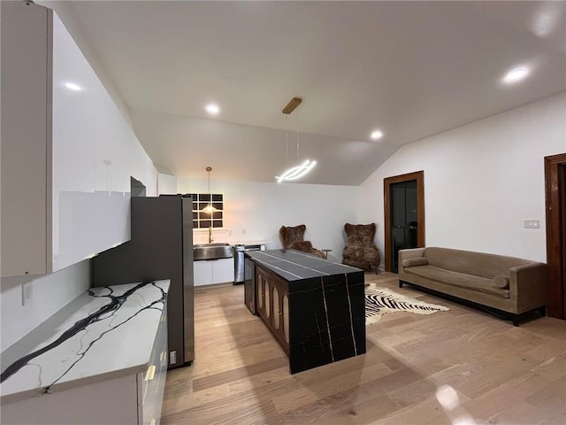 1819 Baronne St, New Orleans, LA 70113 - kitchen with light wood-type flooring, white cabinets, a kitchen island, a sink, and lofted ceiling
