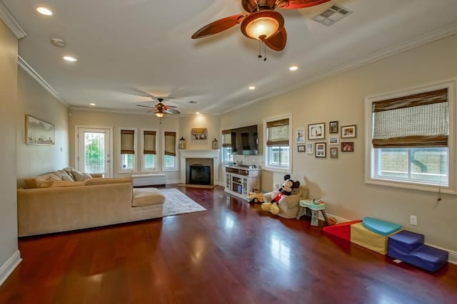 living room featuring ceiling fan, crown molding, a fireplace with flush hearth, wood finished floors, and recessed lighting