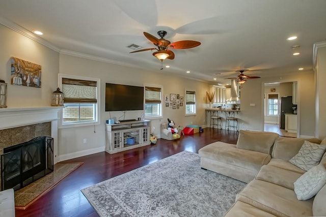 living area with a premium fireplace, ceiling fan, wood finished floors, baseboards, and recessed lighting