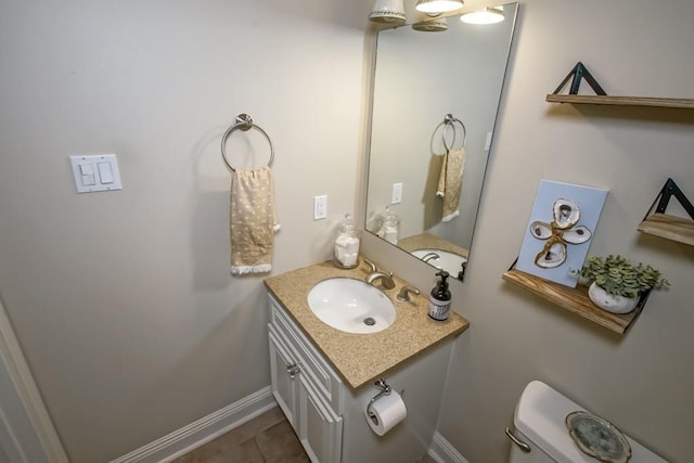 half bathroom featuring vanity, toilet, baseboards, and tile patterned floors