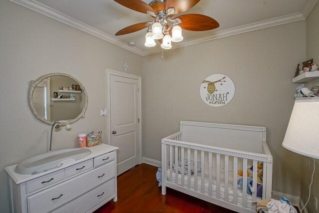 bedroom with a crib, ornamental molding, a sink, dark wood-style flooring, and a ceiling fan