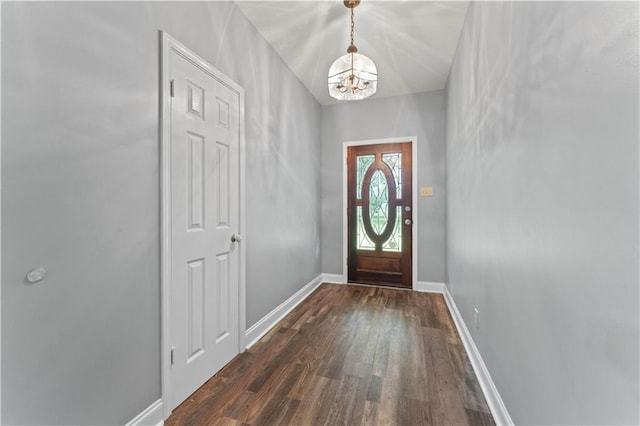 entryway with dark wood-style flooring, a chandelier, and baseboards
