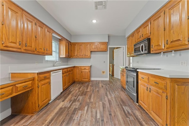 kitchen featuring stainless steel appliances, dark wood-style flooring, brown cabinets, baseboards, and light countertops