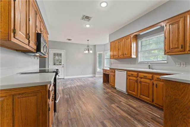 kitchen with appliances with stainless steel finishes, brown cabinets, a chandelier, light countertops, and dark wood-type flooring