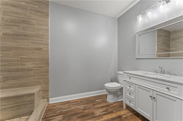 bathroom featuring toilet, vanity, wood finished floors, and baseboards
