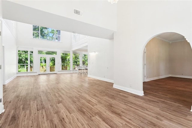 436 Nighthawk Dr, Slidell, LA 70461 - unfurnished living room with a towering ceiling, baseboards, plenty of natural light, arched walkways, and wood finished floors