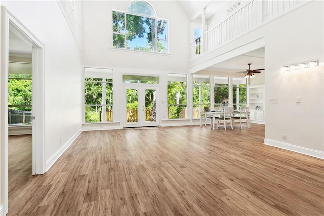 436 Nighthawk Dr, Slidell, LA 70461 - unfurnished living room featuring a towering ceiling, ceiling fan, baseboards, wood finished floors, and french doors