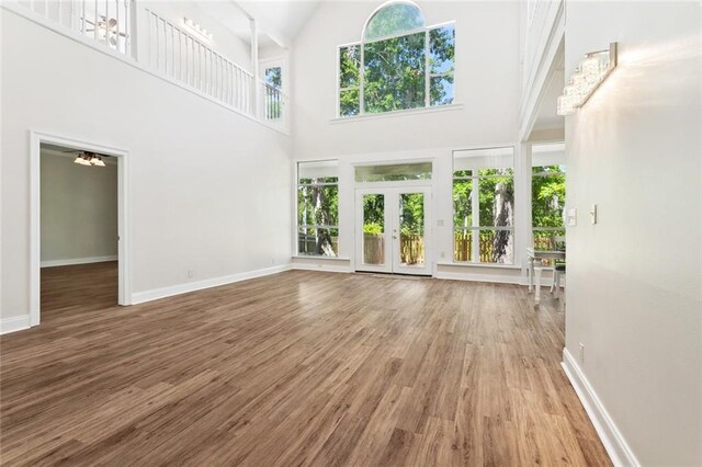436 Nighthawk Dr, Slidell, LA 70461 - unfurnished living room featuring plenty of natural light, high vaulted ceiling, wood finished floors, baseboards, and french doors