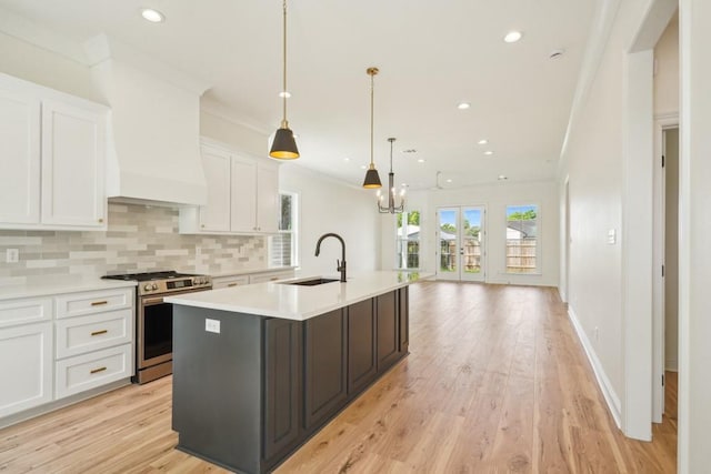 342 W Ave, Harahan, LA 70123 - kitchen with a sink, stainless steel gas range oven, light countertops, a kitchen island with sink, and white cabinetry