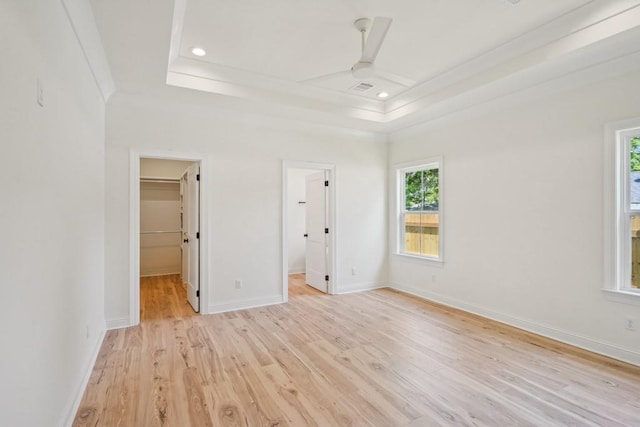 342 W Ave, Harahan, LA 70123 - unfurnished bedroom with a walk in closet, crown molding, light wood-style floors, a raised ceiling, and baseboards
