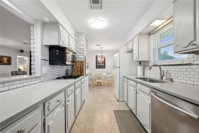 1513 Belmont Pl, Metairie, LA 70001 - kitchen featuring stainless steel appliances, a sink, backsplash, a chandelier, and light countertops