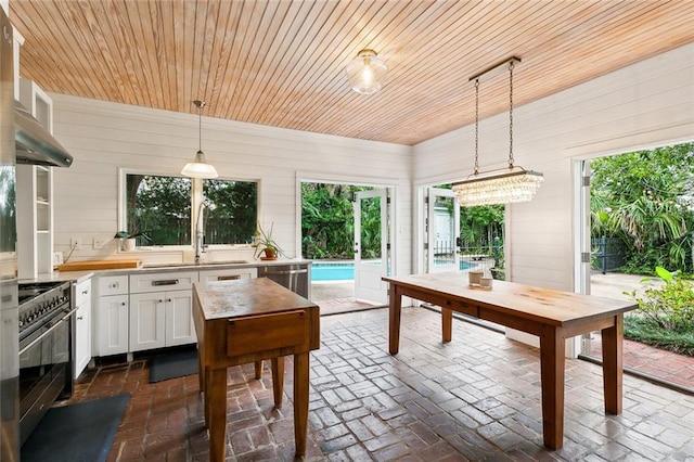 1612 Milan St, New Orleans, LA 70115 - kitchen with stainless steel appliances, a sink, brick floors, light countertops, and white cabinetry