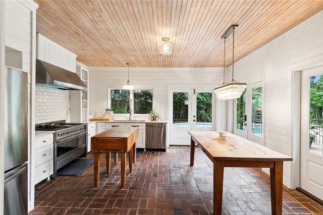 1612 Milan St, New Orleans, LA 70115 - kitchen with stainless steel appliances, wall chimney exhaust hood, wooden ceiling, light countertops, and brick floors