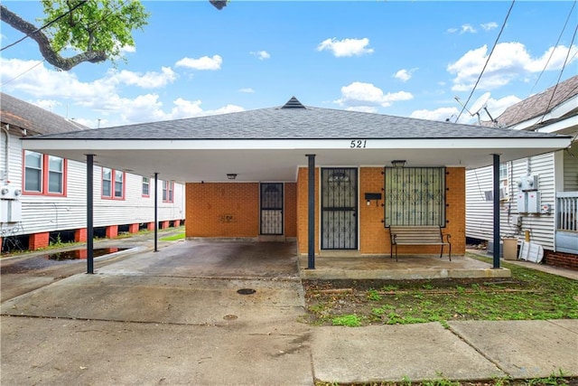 521 S Alexander St, New Orleans, LA 70119 - view of front of property featuring a shingled roof, concrete driveway, a carport, and brick siding