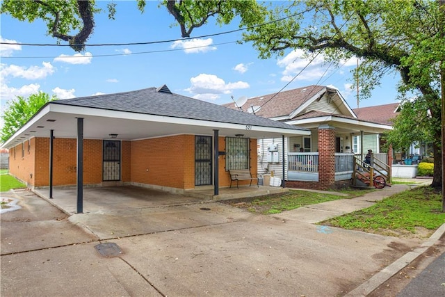 521 S Alexander St, New Orleans, LA 70119 - view of front of property with brick siding, covered porch, a shingled roof, a carport, and driveway