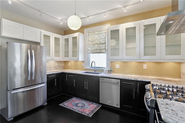 7715 Panola St, New Orleans, LA 70118 - kitchen with stainless steel appliances, a sink, wall chimney exhaust hood, track lighting, and white cabinetry