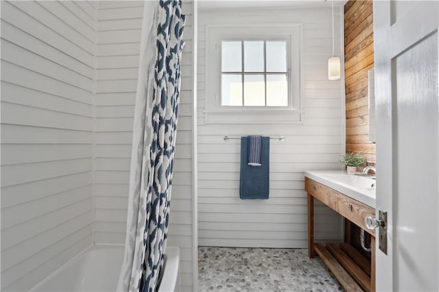 7715 Panola St, New Orleans, LA 70118 - bathroom with wood walls, shower / tub combo with curtain, vanity, and speckle patterned floor