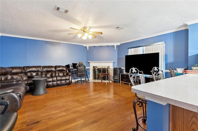 2929 Hudson St, New Orleans, LA 70114 - living area featuring ornamental molding, wood finished floors, a ceiling fan, a textured ceiling, and a fireplace with flush hearth