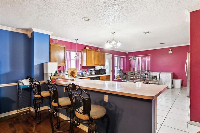 2929 Hudson St, New Orleans, LA 70114 - kitchen with a textured ceiling, a chandelier, light countertops, brown cabinets, and a peninsula