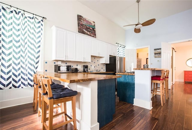 1241 Kerlerec St, New Orleans, LA 70116 - kitchen with wood counters, appliances with stainless steel finishes, a breakfast bar, a towering ceiling, and dark wood-type flooring