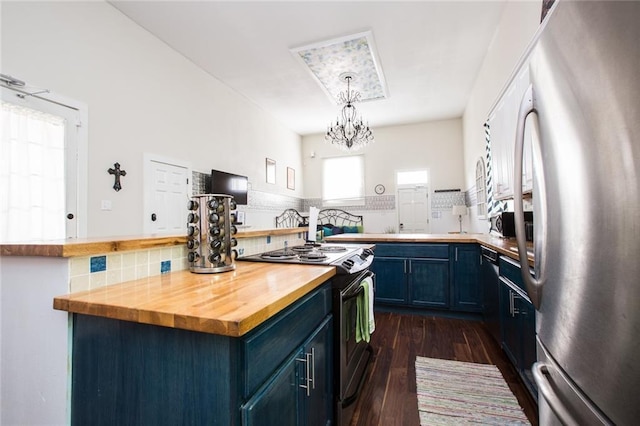 1241 Kerlerec St, New Orleans, LA 70116 - kitchen with freestanding refrigerator, electric stove, butcher block counters, blue cabinets, and backsplash