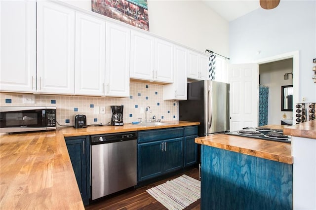 1241 Kerlerec St, New Orleans, LA 70116 - kitchen with butcher block counters, appliances with stainless steel finishes, a sink, white cabinetry, and a towering ceiling