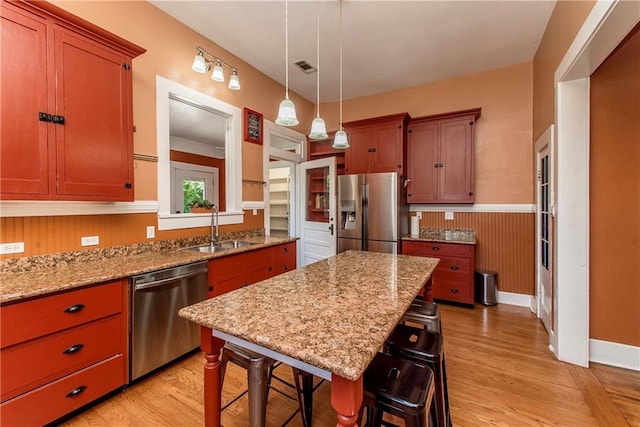 245 E Oak St, Ponchatoula, LA 70454 - kitchen featuring appliances with stainless steel finishes, a sink, light wood finished floors, a breakfast bar area, and wainscoting