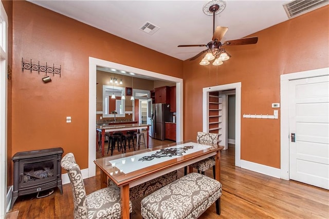 245 E Oak St, Ponchatoula, LA 70454 - dining area with a wood stove, a ceiling fan, wood finished floors, and baseboards